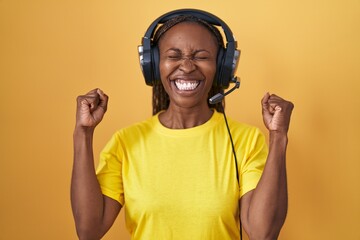 Poster - African american woman listening to music using headphones excited for success with arms raised and eyes closed celebrating victory smiling. winner concept.