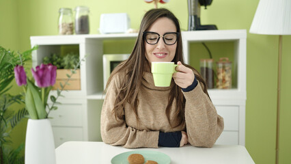 Wall Mural - Beautiful hispanic woman drinking coffee sitting on table at dinning room