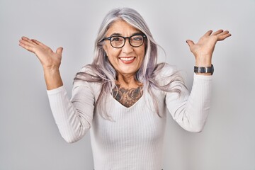 Wall Mural - Middle age woman with grey hair standing over white background celebrating crazy and amazed for success with arms raised and open eyes screaming excited. winner concept