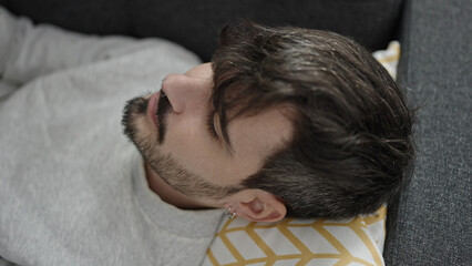 Wall Mural - Young hispanic man relaxed lying on sofa at home