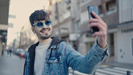 Sticker - Young hispanic man smiling confident making selfie with smartphone at street