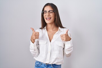 Canvas Print - Young brunette woman wearing glasses success sign doing positive gesture with hand, thumbs up smiling and happy. cheerful expression and winner gesture.