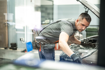 the mechanic fixes the car taking the tools from the table