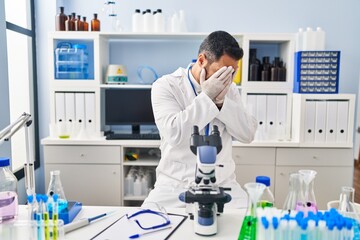 Poster - Young hispanic man with beard working at scientist laboratory with sad expression covering face with hands while crying. depression concept.