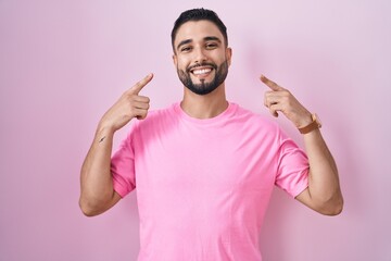 Poster - Hispanic young man standing over pink background smiling pointing to head with both hands finger, great idea or thought, good memory