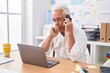 © Krakenimages.com - Middle age grey-haired man business worker using laptop talking on smartphone at office