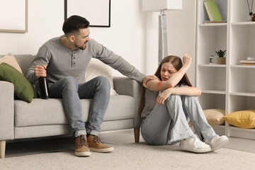 Wall Mural - Bruised young woman and her drunk husband at home. Domestic violence concept