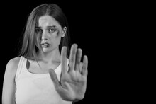 Bruised Young Woman Showing Stop Gesture On Dark Background. Domestic Violence Concept
