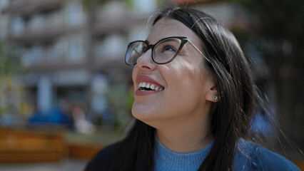 Wall Mural - Young hispanic woman smiling confident looking up at street