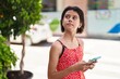 © Krakenimages.com - Adorable hispanic girl using smartphone with serious expression at street