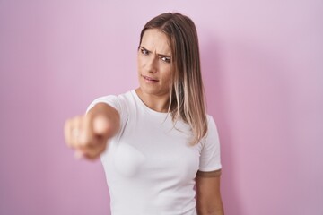 Poster - Blonde caucasian woman standing over pink background pointing displeased and frustrated to the camera, angry and furious with you