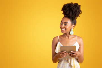 Wall Mural - Cheerful millennial african american woman typing on tablet, look at empty space