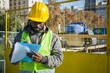 young black male construction worker in his outdoor workspace making notes in a folder