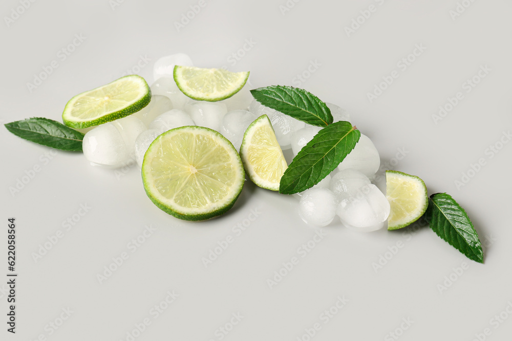 Lime slices with ice cubes and mint on grey background