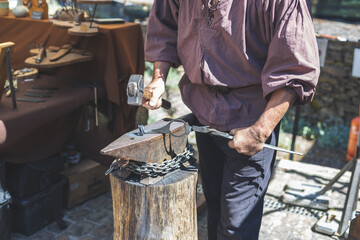 Caucasian male blacksmith forges iron in an anvil.