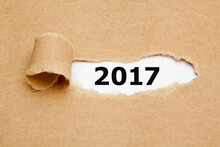 Year 2017 Appearing Behind Ripped Brown Paper.