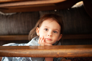 Portrait of a cute little girl sitting on the stairs and looking at the camera