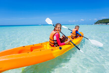 Kids Enjoying Paddling In Orange Kayak At Tropical Ocean Water During Summer Vacation