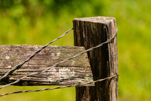 The Corner Of A Wooden Fence Marking The Boundaries Of An Livestock Farm Ranches Pasture Corral Pen, With The Wooden Lumber Pieces Tied Together By Thin Gage Steel Wire  Wrapped Around The Post