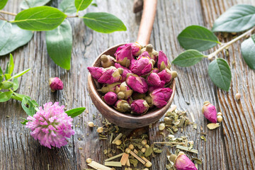 Wall Mural - Dry flower rose tea buds in a wooden spoon. Concept of well-being, colors, dieting and healthy lifestyle