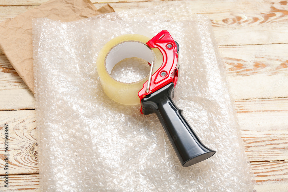 Packing tape dispenser and bubble wrap on wooden background