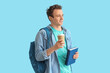 © Pixel-Shot - Male student with backpack, books and cup of coffee on blue background