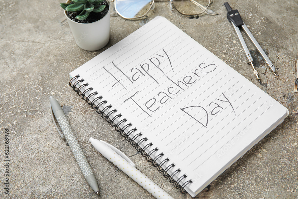 Notebook with text HAPPY TEACHERS DAY, eyeglasses and different stationery on grunge grey background