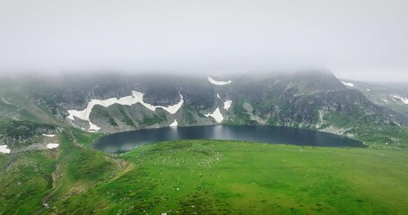 Wall Mural - mountain lake in fog and peaks in snow, panorama aerial view nature wilderness landscape 4k video