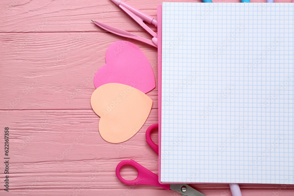 Blank notebook and different stationery on pink wooden background