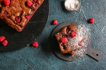 Boards with pieces of raspberry chocolate brownie on dark table