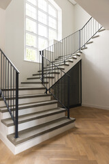 Large window and staircase in sunny hallway of house with wood paneled flooring, copy space