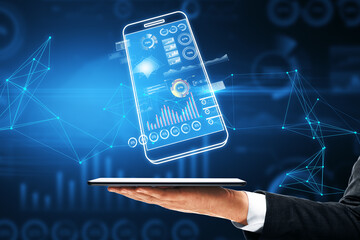 Wall Mural - Close up of businessman hand holding digital blue smartphone with business chart on dark polygonal background. Analytics, financial report and money concept.