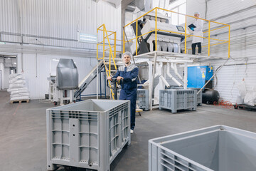 Wall Mural - Man loader in uniform working trolley with wheat in warehouse. Industrial manufacturing factory flour mill