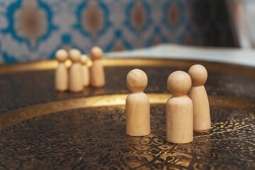 wooden figurines of people on the table. subject photo session of humanoid toys in the room. wooden toys on a bronze plate