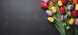 Fototapeta Tulipany - Blooming flowes spring background banner - Colorful tulips, on dark black concrete table, top view (Generative Ai)