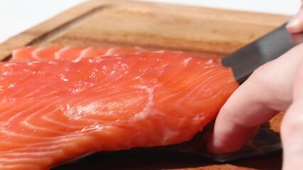 Wall Mural - A girl chef cut the skin of a salmon fillet.  raw red fish fillets lies on the kitchen wooden board. Raw salmon