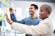 © Malambo C/peopleimages.com - Happy creative people, writing and glass board for schedule planning, strategy or brainstorming at office. Man and woman in teamwork for startup project plan, sticky note or tasks at the workplace