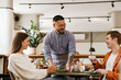 © Drobot Dean - Smiling waiter serving couple in cafe