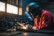 Male in face mask welds with argon arc welding.
