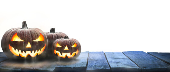 Wall Mural - three lit jack-o-lantern, halloween pumpkin lanterns on a wooden product display table with an isola