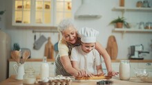 Granny And Granddaughter Pre-teen Girl Cooks Homemade Cookies In Kitchen At Home Together. Family Recipe, Sweets And Bakery, Preparing Fresh Food. They Squeeze Out Cookies Star Shape From Dough.