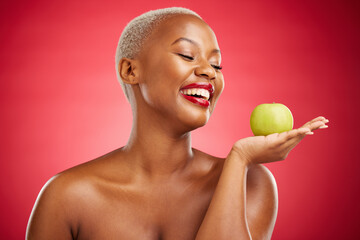 Wall Mural - Happy black woman, apple and natural nutrition for diet, health and wellness against a red studio background. African female person smile and palm with organic green fruit for food, snack or meal