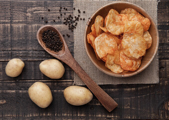 Bowl with potato crisps chips with pepper on wood. Potatoes and pepper