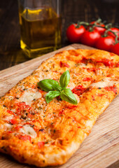 Wall Mural - Pizza bread with tomatoes and olive oil on wooden board. With basil on top