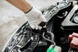 Close-up of hand of a gloved mechanic opening the radiator cap to check the coolant level. A man's hand is holding the radiator cap and opening it to check the water in the engine. car maintenance