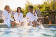 © Monkey Business - Group Of Mature Female Friends Wearing Robes Sitting With Feet In Pool Drinking Champagne On Spa Day