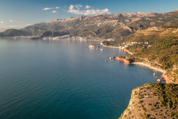 Aerial view of the famous tourist location Sveti Stefan island in the distance and picturesque Adriatic coastline near the city of Budva, Montenegro.