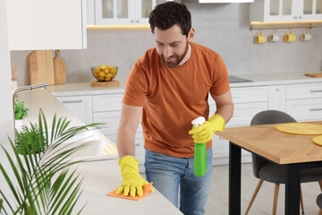 Wall Mural - Spring cleaning. Man tidying up kitchen at home