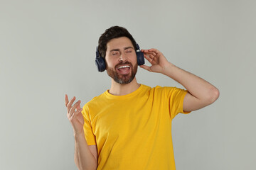 Canvas Print - Happy man listening music with headphones on light grey background