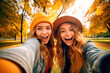Leinwandbild Motiv Two funny girls taking a selfie in a forest in autumn